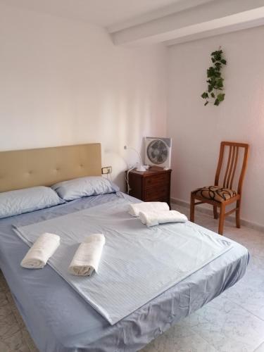 瓦伦西亚PISO EN MALVARROSA的卧室内的一张带两个枕头和椅子的床