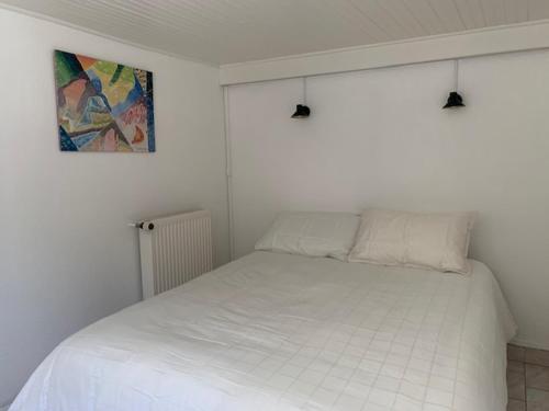 滨海圣洛朗INTERLUDE omaha beach 50 m de la plage的白色卧室内的一张白色床,墙上挂着一幅画