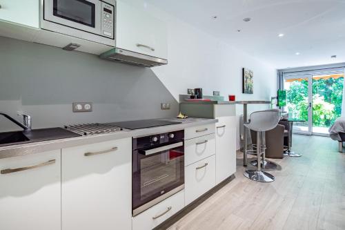 BoerschWellholidays 19 - studio balnéo et terrasse piscine的厨房配有白色橱柜和炉灶烤箱。