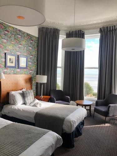 伊斯特布恩West Rocks Townhouse的酒店客房带两张床、一张沙发和椅子。