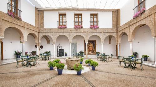 科尔多瓦NH收藏阿米斯塔德科尔多瓦酒店的大房间设有桌椅和绘画作品