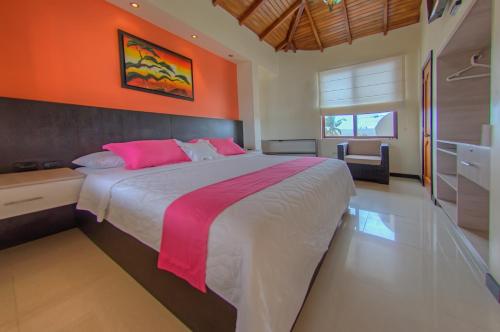 比亚米尔港加拉帕戈斯圣维森特饭店的一间卧室配有一张带橙色墙壁的大床