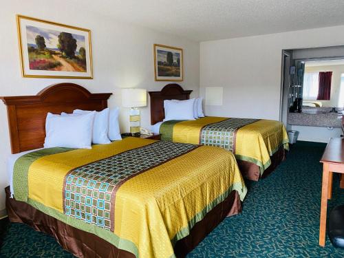 HarrisonvilleHarrisonville Inn & Suites的配有黄色床单的酒店客房的两张床