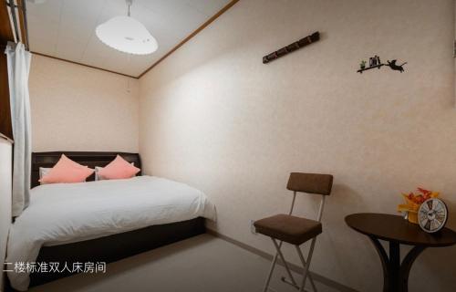 大阪10mins train to Namba, 4 mins walk to stn, 2 floors japanese style , 2-8 people的一间卧室配有一张带粉红色枕头的床和一张桌子