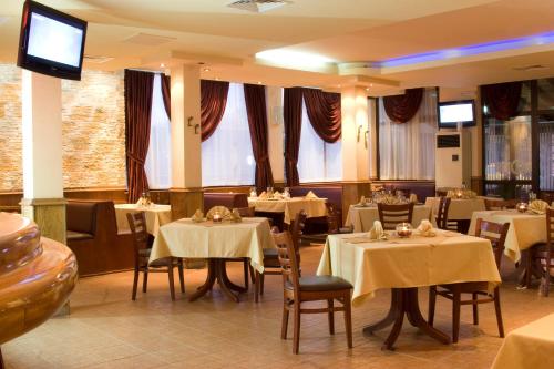 布尔加斯阿维纽酒店的餐厅设有白色的桌椅和窗户。
