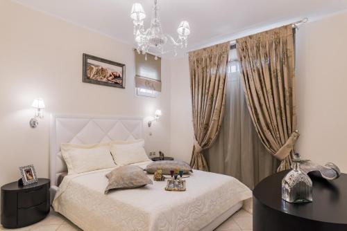 FlókaFaidra Luxury Apartment的卧室配有白色的床和吊灯。