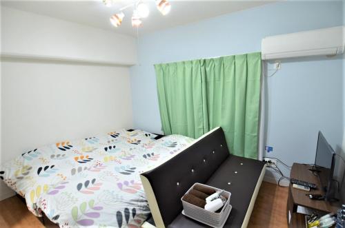 宫崎Comfort CUBE PHOENIX MIYAZAKI的一间卧室配有床、电视和绿色窗帘