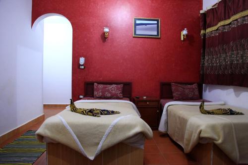 Bawati西部沙漠酒店及野生动物园的红色墙壁的客房内的两张床