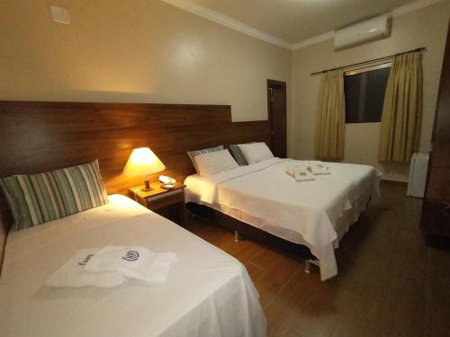 乌贝拉巴Hotel Albatroz的酒店客房,设有两张床和一盏灯