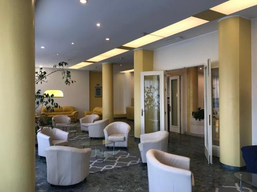 因佩里亚罗比尼亚酒店的一间设有白色椅子和桌子的等候室
