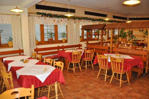 卢布尔雅那克梅茨基赫拉姆旅馆的餐厅配有桌椅和红色桌布