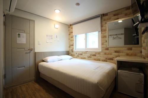 首尔东大门华新旅馆的一间小卧室,配有床和窗户