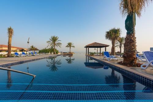 乌姆盖万Barracuda Resort的一个带椅子的游泳池,棕榈树