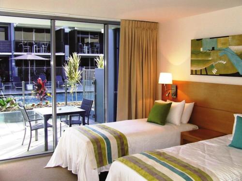 赫维湾华美达赫维湾酒店的酒店客房设有两张床、一张桌子和一个阳台。