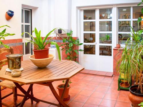 塞维利亚Belvilla by OYO Preciosa casa en Sevilla的庭院里种植了盆栽植物,配有木桌