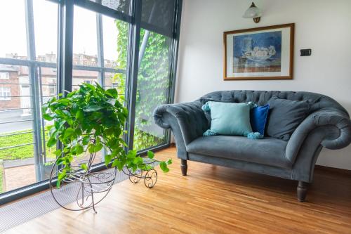 卡托维兹Aparthotel Hornigold "W Zielonej Kamienicy"的带沙发和盆栽植物的客厅
