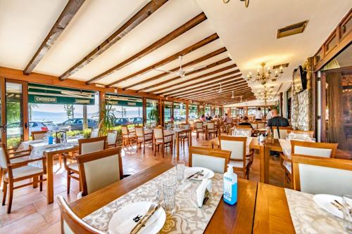奥赫里德Tino Hotel & SPA的餐厅设有木桌、椅子和窗户。