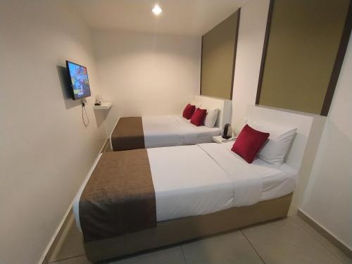 努沙再也Crescendo Boutique Hotel的酒店客房 - 带两张带红色枕头的床