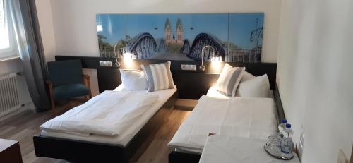 弗莱堡Hotel Bären Garni的配有2张床的带白色床单和枕头的客房