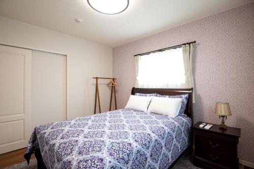 今归仁村MAKAI green的一间卧室配有一张带蓝色棉被的床和窗户。