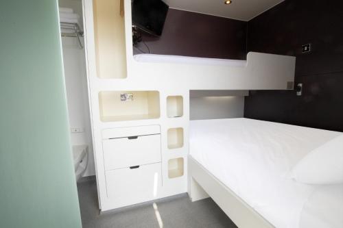 伦敦Snoozebox Olympic Park的一间小卧室,配有白色的橱柜和一张床