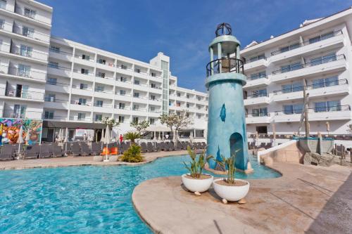皮内达德马尔30º Hotels - Hotel Pineda Splash的一座灯塔,位于一座建筑物前的游泳池中间