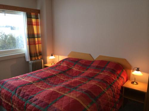 VormsundVormsund Golf Hotell的一间卧室配有一张带五颜六色的被子和两盏灯的床。