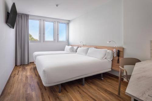 里斯本B&B HOTEL Lisboa Aeroporto的卧室配有一张白色的大床和一张桌子