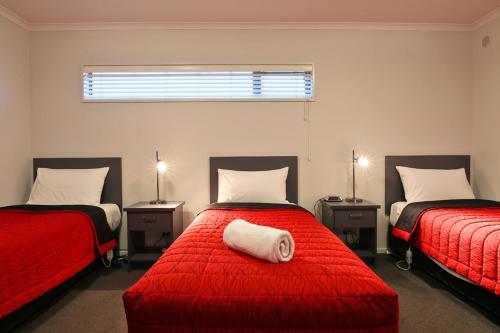 奥玛鲁奥玛鲁汽车旅馆的一间卧室配有两张带红色床单和白色枕头的床