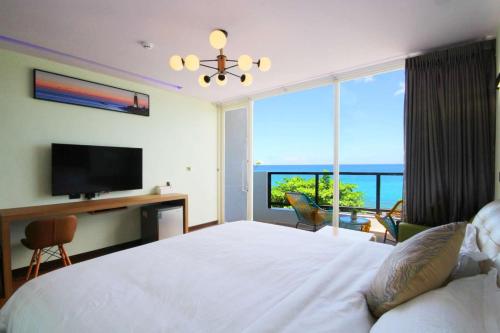 车城墾丁 後灣 微風海岸海景民宿的一间卧室设有一张床、一台电视和一个窗口。