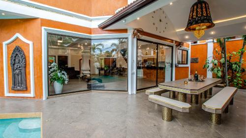 南芭堤雅TUCHELAND Luxury Pool Villa Pattaya Walking Street 7 Bedrooms的一间位于房子内的带桌子和长凳的用餐室