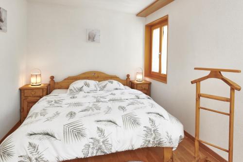 莱迪亚布勒雷Magnifique appartement aux Diablerets avec vue imprenable的一间卧室配有一张带白色被子和两盏灯的床。