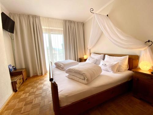 沃尔特湖畔韦尔登Pleschinhof的卧室配有带白色枕头的天蓬床