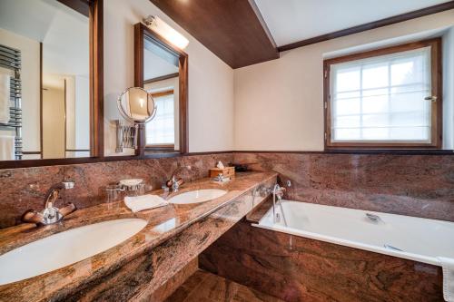 夏蒙尼-勃朗峰奥贝奇酒店的浴室配有2个盥洗盆、浴缸和大镜子