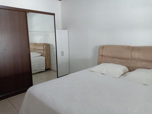 伊瓜苏Casa Aconchego Fóz的卧室配有白色的床和镜子