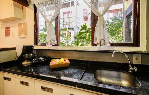 布希奥斯Excelente Casa Duplex Búzios/Geribá, WI FI, churrasqueira privativa的厨房配有水槽和柜台上的一碗水果