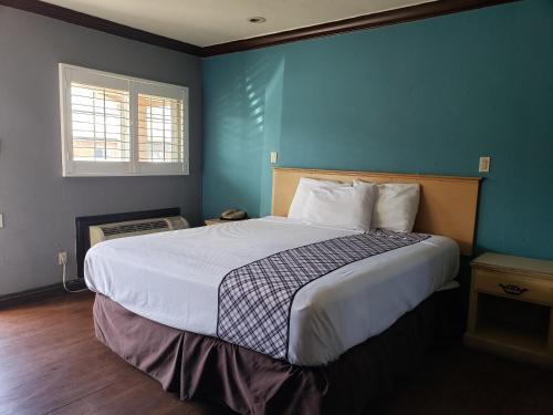 长滩金鹰汽车旅馆的一间卧室设有一张蓝色墙壁的大床