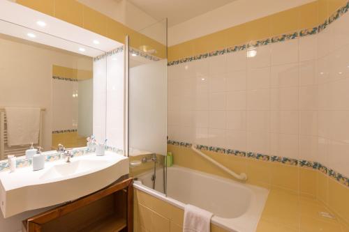 拉普拉涅Résidence Pierre & Vacances Le Mont Soleil的一间带水槽、浴缸和镜子的浴室