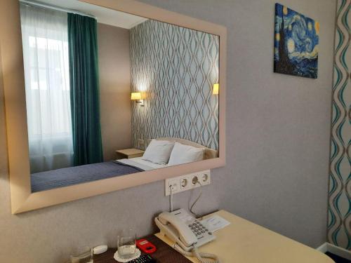 敖德萨Hotel Ajur的一间卧室配有镜子和一张书桌上的电话