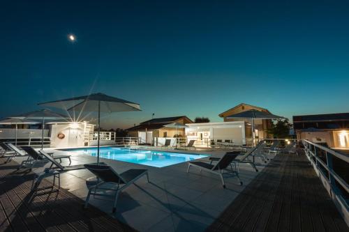 萨维奥迪拉韦纳Ca' Mira - Room&Breakfast的游泳池在晚上提供椅子和遮阳伞