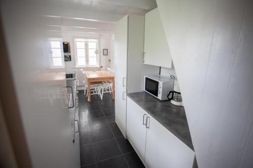 托尔斯港Two Bedroom Vacation Home in the Center of Tórshavn的厨房配有白色橱柜和带微波炉的桌子。