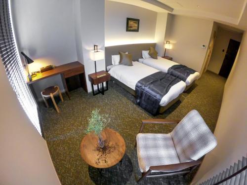 大阪Hotel S-Presso South的酒店客房,配有一张床、一张桌子和椅子