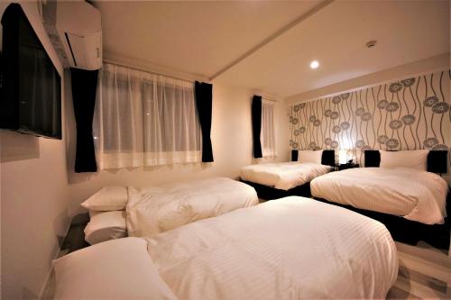 小樽Cozy Inn OTARU的酒店客房设有三张床和电视。