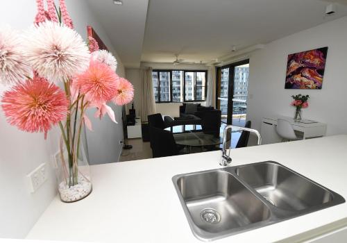 达尔文WATERFRONT DARWIN TROPICAL DELIGHT的花瓶里带水槽和粉红色花卉的厨房台面