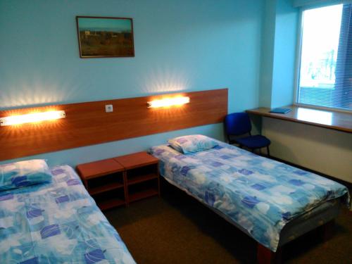 维尔扬迪曼尼玛宾馆的一间卧室设有两张床、一张桌子和一个窗口。