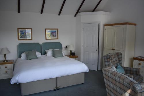 卡迪根Cardigan Castle的一间卧室配有一张大床和一把椅子
