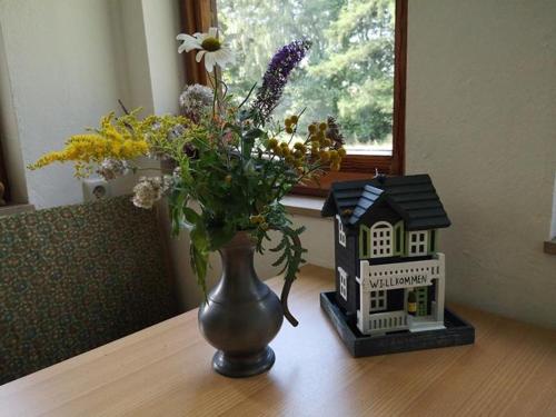 新基兴Ferienwohnung Bachforelle的花瓶放在房子旁边的桌子上