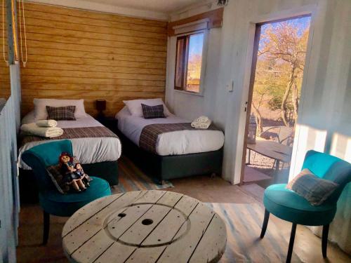圣佩德罗·德·阿塔卡马Atacama Loft & Glamp的一间设有两张床和一张桌子及椅子的房间