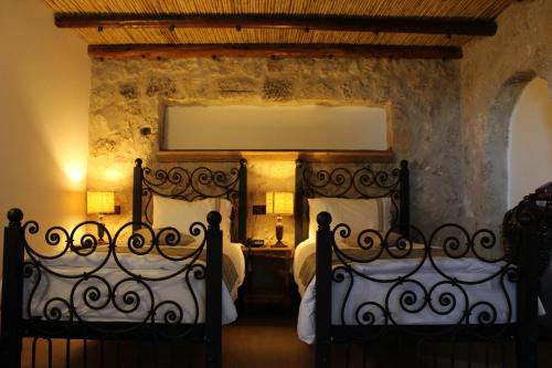 凯里尼亚科莫利康纳克精品酒店的卧室设有两张床铺和石墙