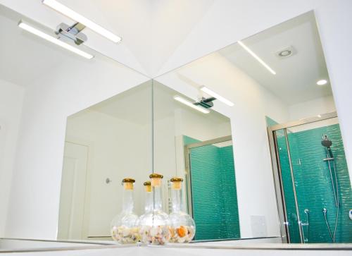 罗马Trastevere Boulevard的浴室镜子,架子上装有四瓶玻璃瓶